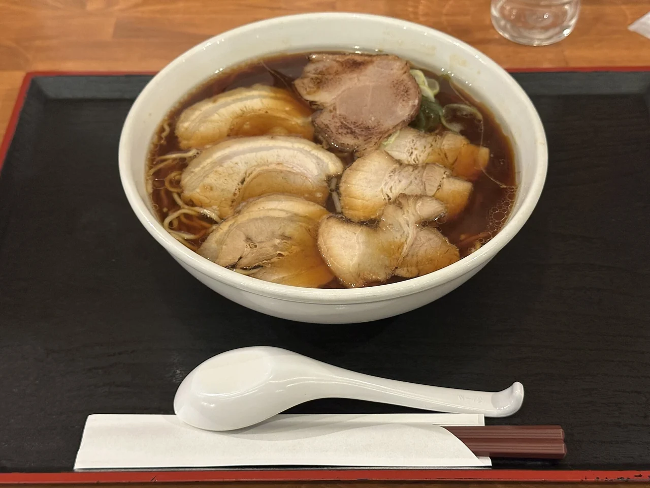 A ramen bowl covered with clearly visible overlapping slices of chashu pork.