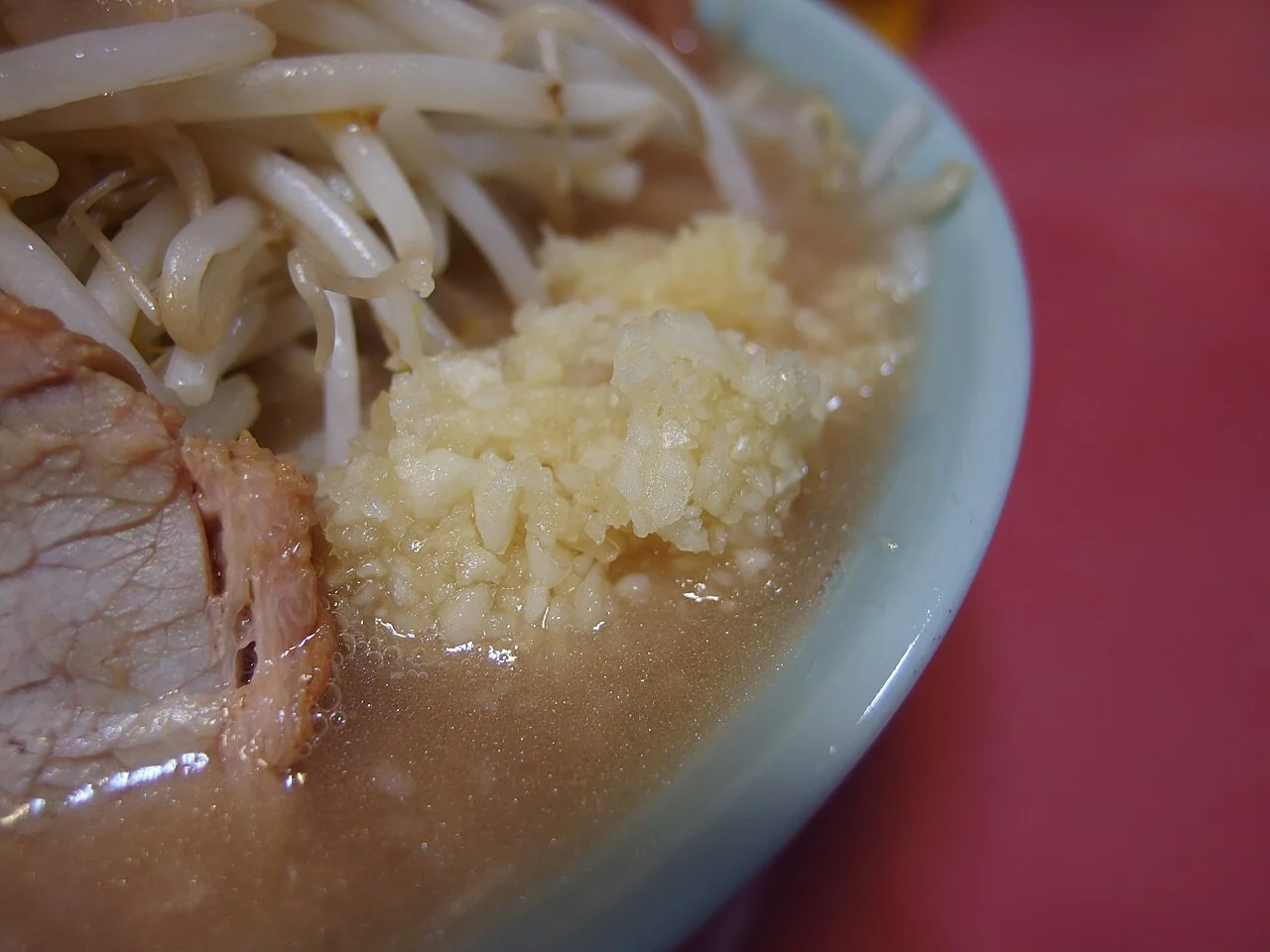 Chopped garlic beside bean sprouts and pork on a bowl at Jiro Kabukicho.
